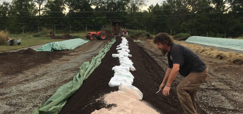 Farmer mixing azomite into a compost windrow