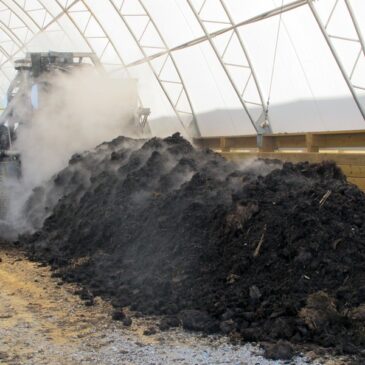 a row of covered compost being turned by a machine