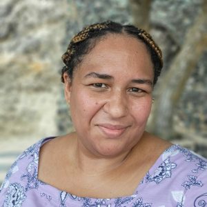 Yesenia Rivera wears her hair in braids pulled back with a middle part, and smiles with lips closed at the camera