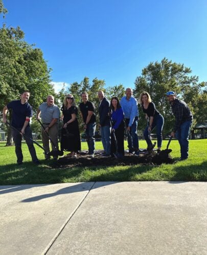 A dozen local officials hold shovels above the ground at Bountiful Fiber groundbreaking ceremony