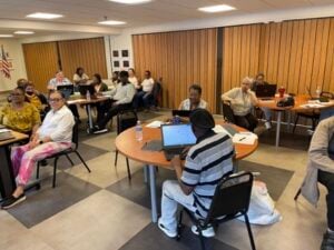 About two dozen mostly older Cleveland residents in Click digital skills class seated around tables, one man is looking at his open laptop