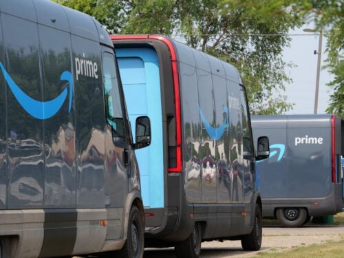 Amazon trucks line up along a tree-lined street. The FTC's Amazon case is a big deal, according to ILSR's Ron Knox.